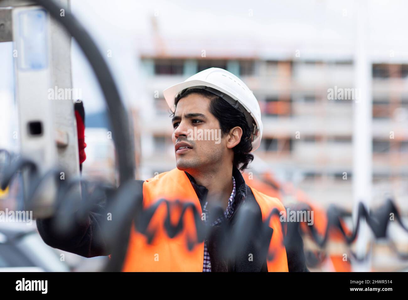 Engineer wearing hardhat examining machinery outdoors Stock Photo