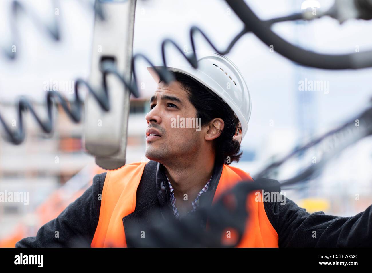 Engineer wearing hardhat examining machinery outdoors Stock Photo