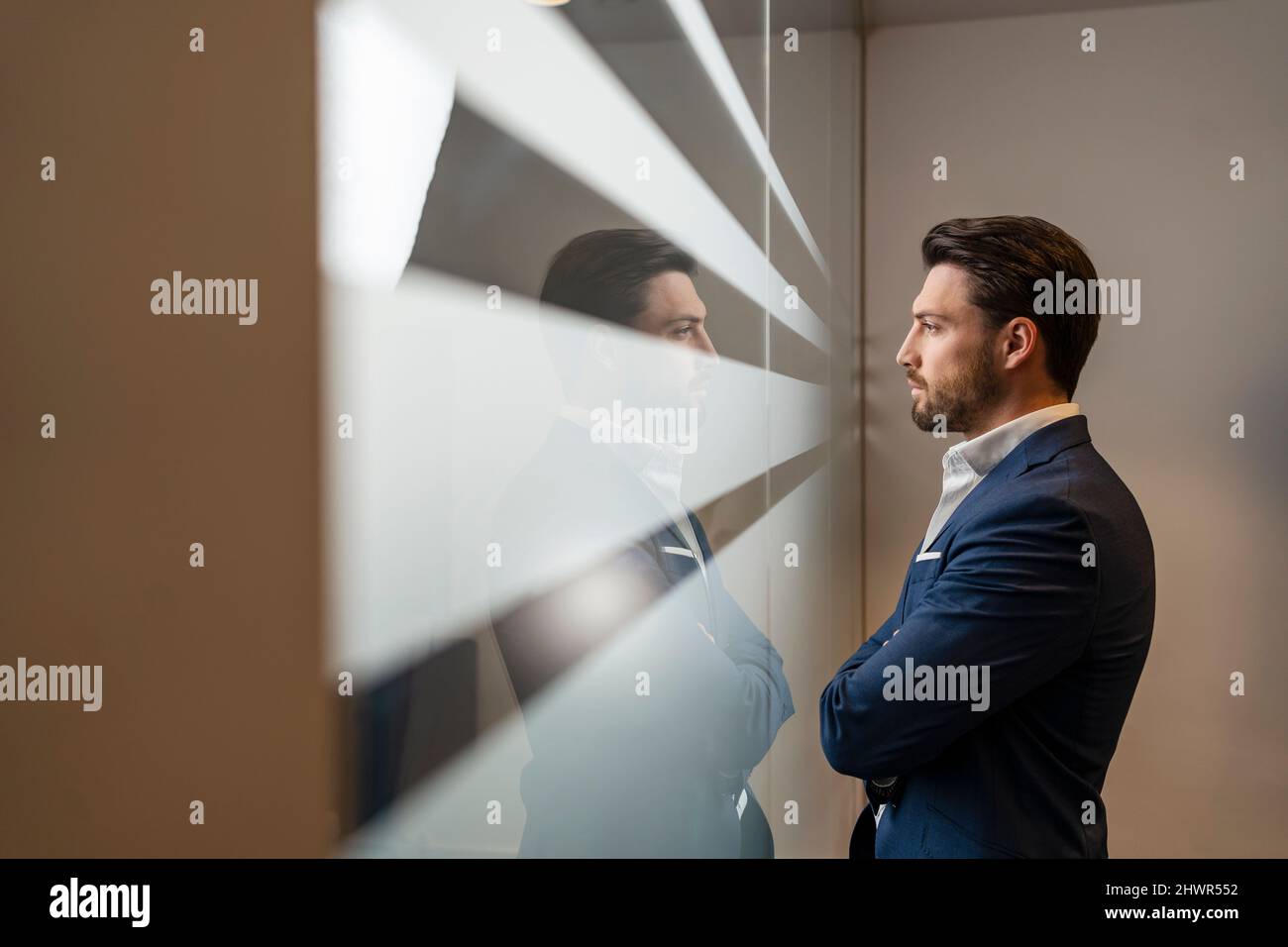 Confident businessman looking through window in office Stock Photo