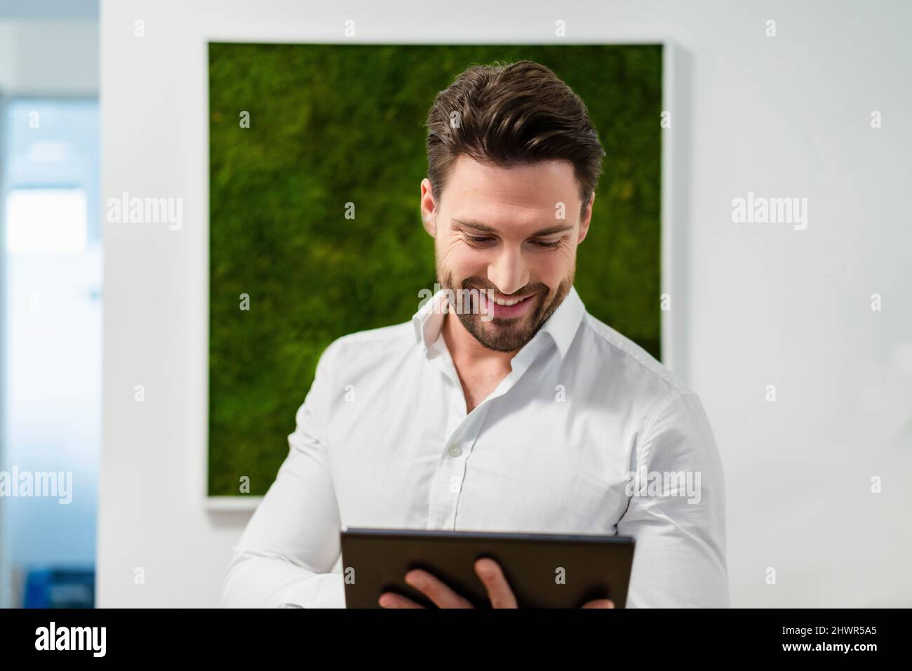 Smiling businessman working on tablet PC in office Stock Photo