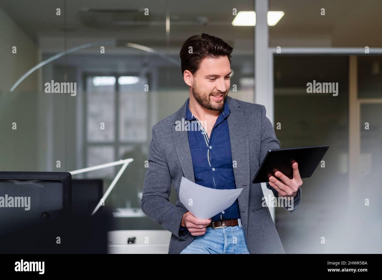 Businessman with document using tablet PC in office Stock Photo