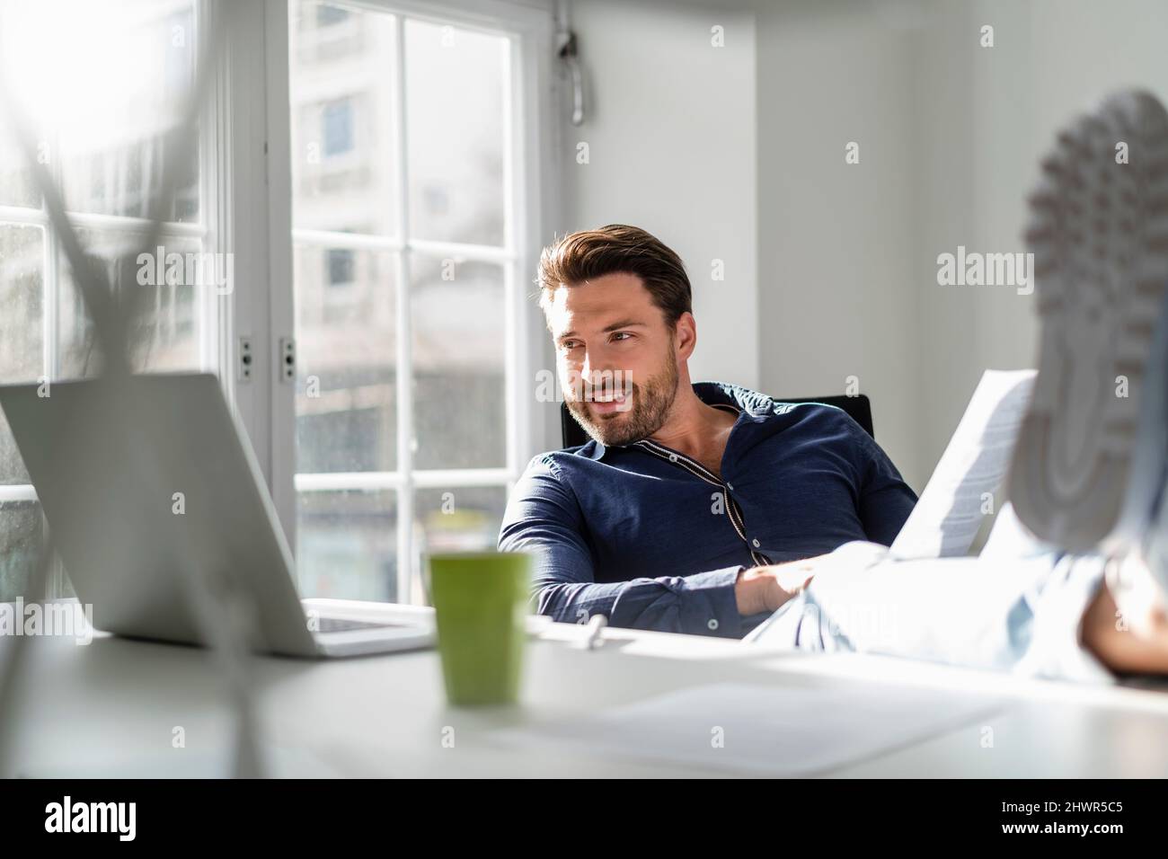 Businessman with document using laptop at office Stock Photo