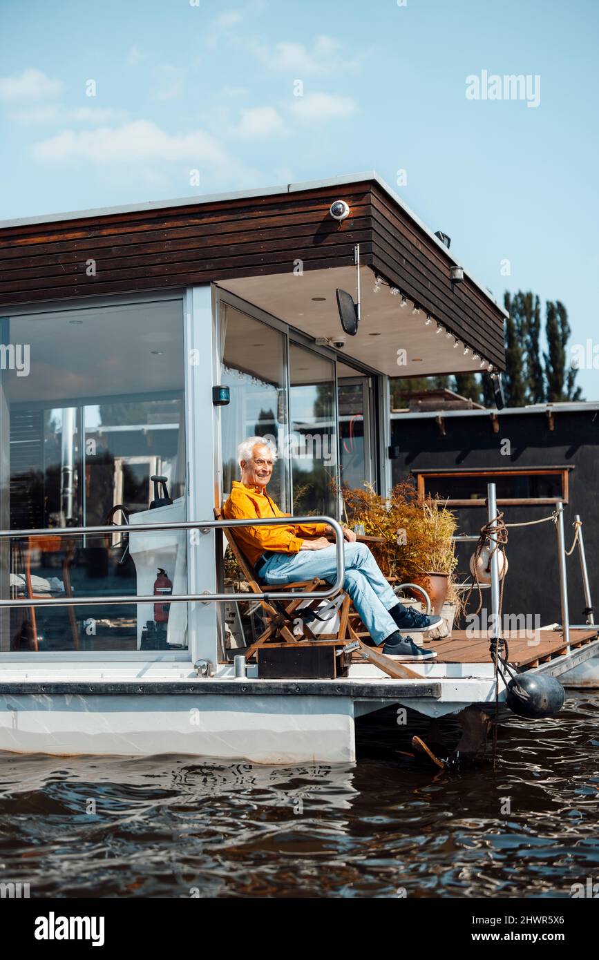 Senior man sitting on chair at houseboat Stock Photo - Alamy