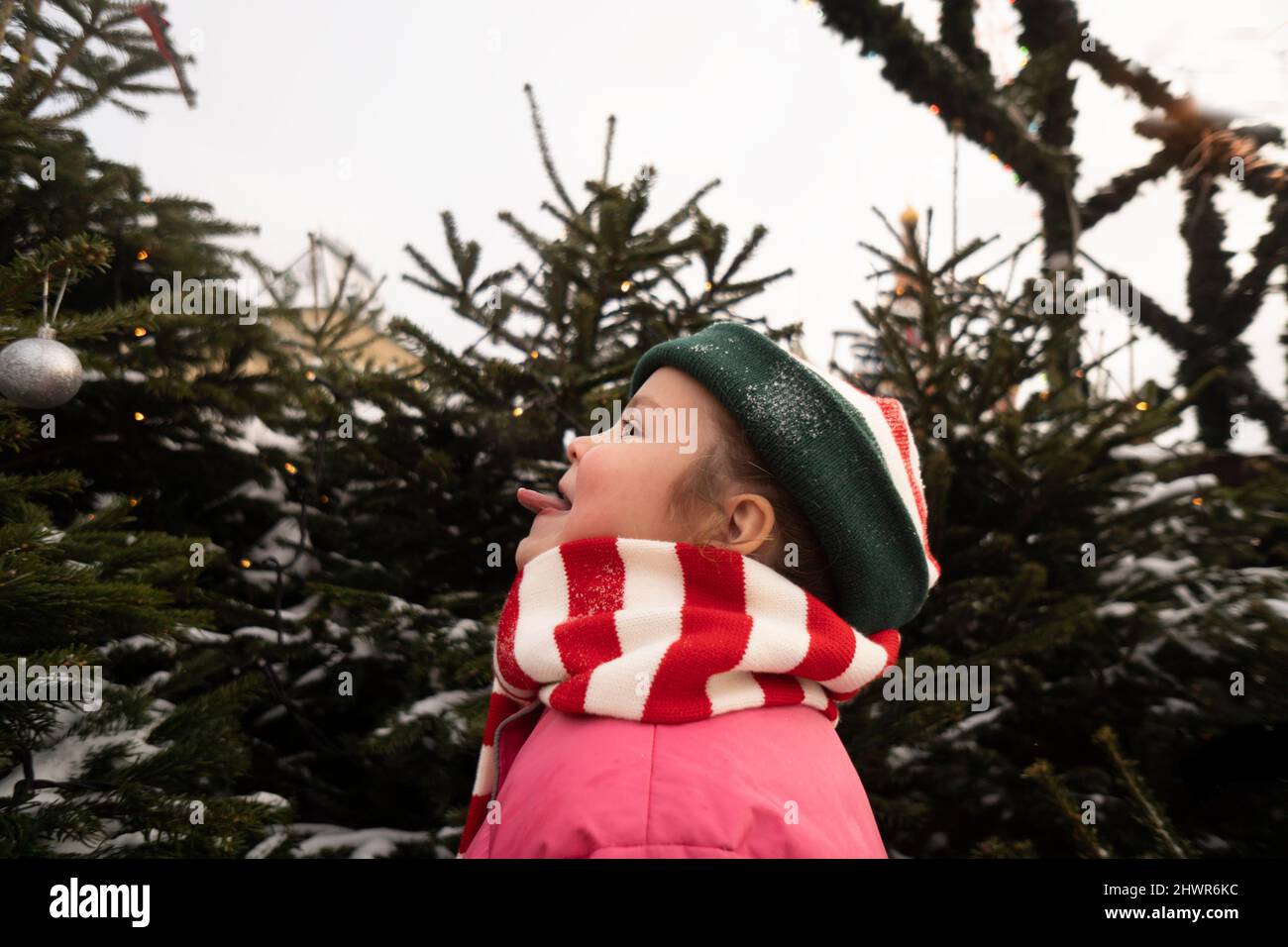 Girl sticking out tongue standing in front of Christmas tree Stock Photo