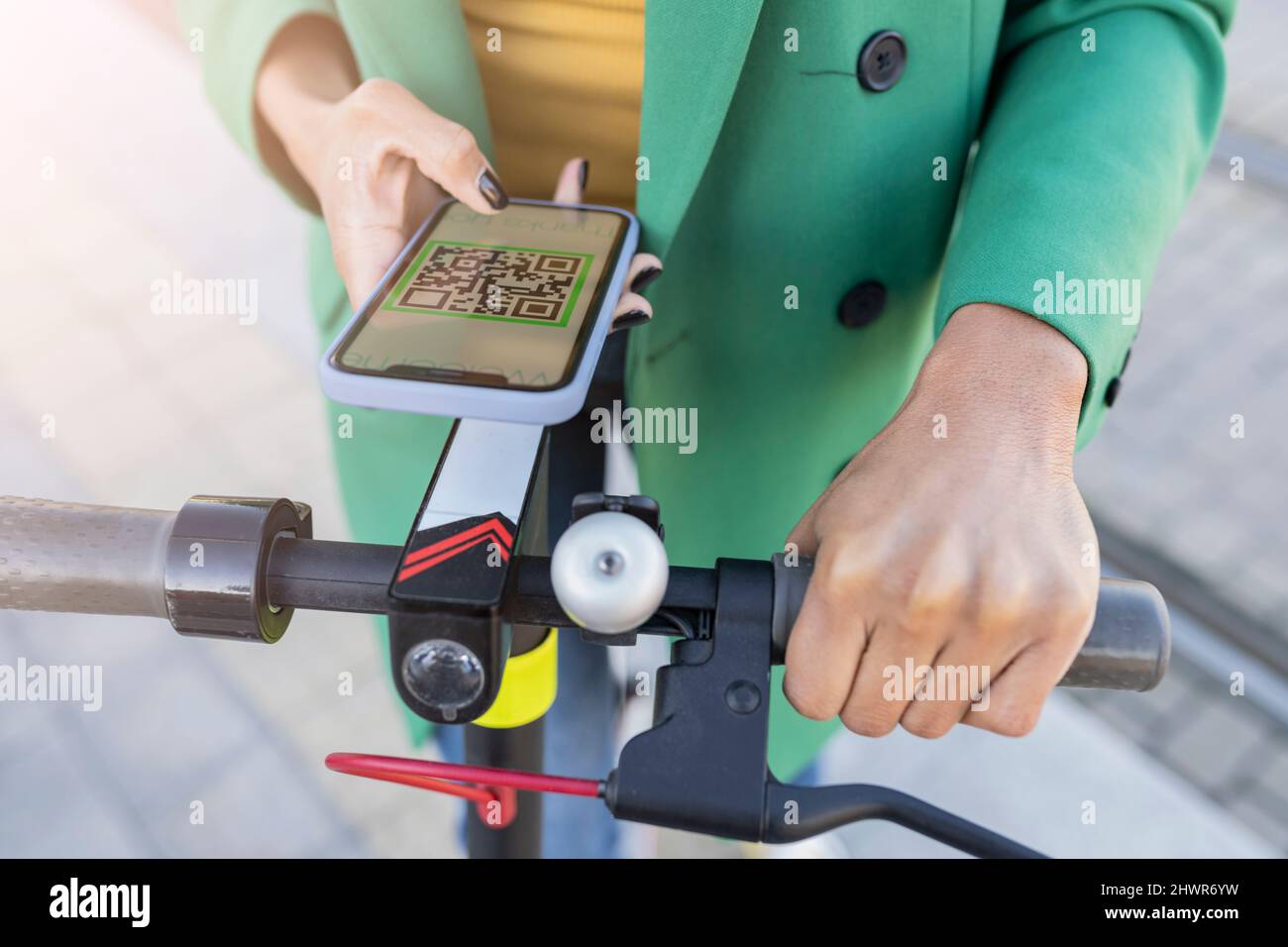 Businesswoman scanning QR code through smart phone on electric push