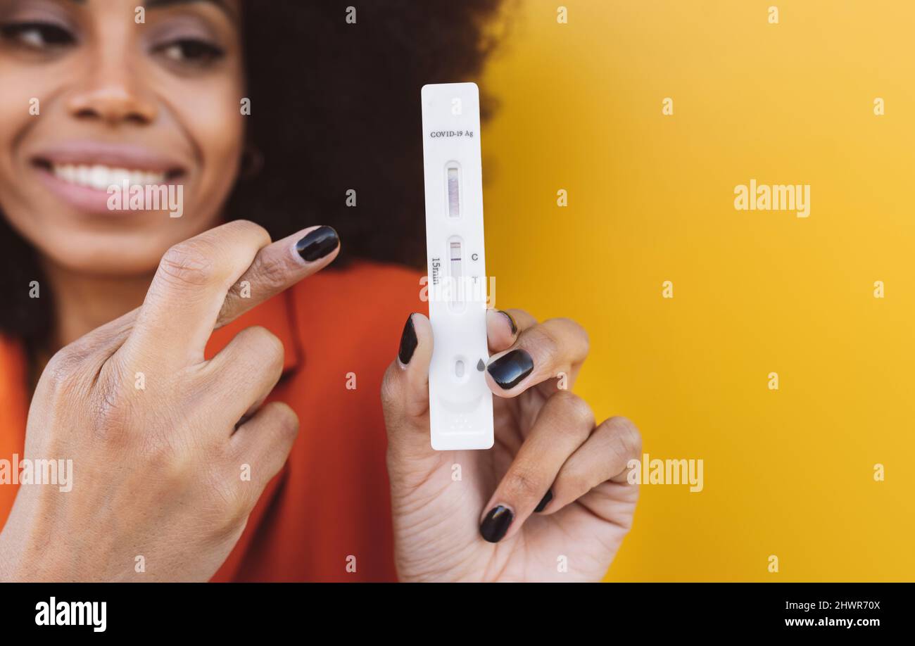 Woman with fingers crossed holding testing kit Stock Photo