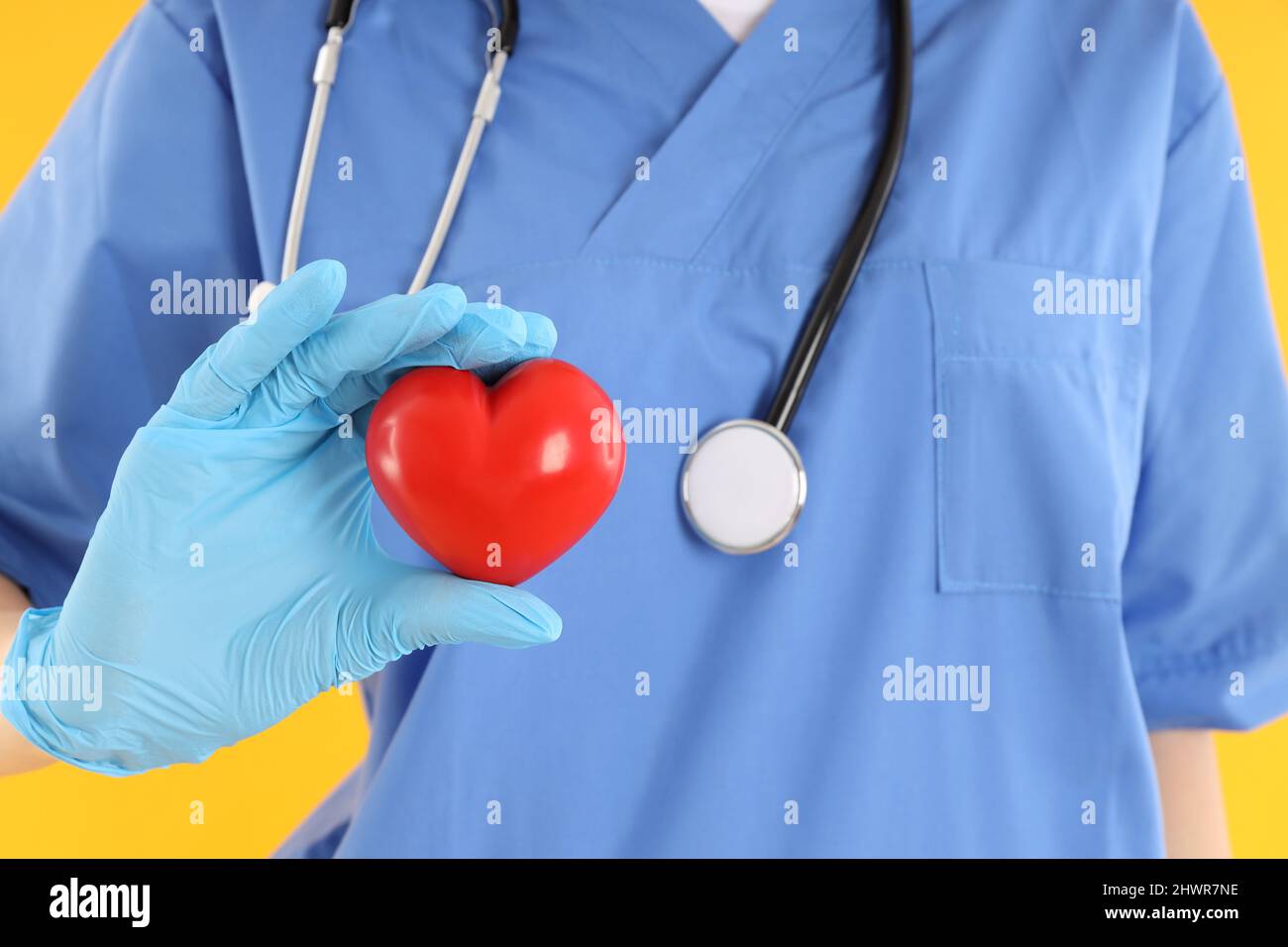 Female doctor holds heart on yellow background Stock Photo