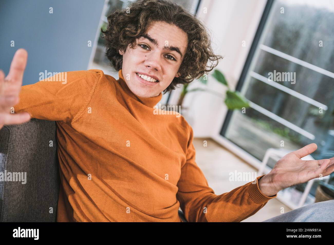 Young man with brown hair gesturing sitting at home Stock Photo