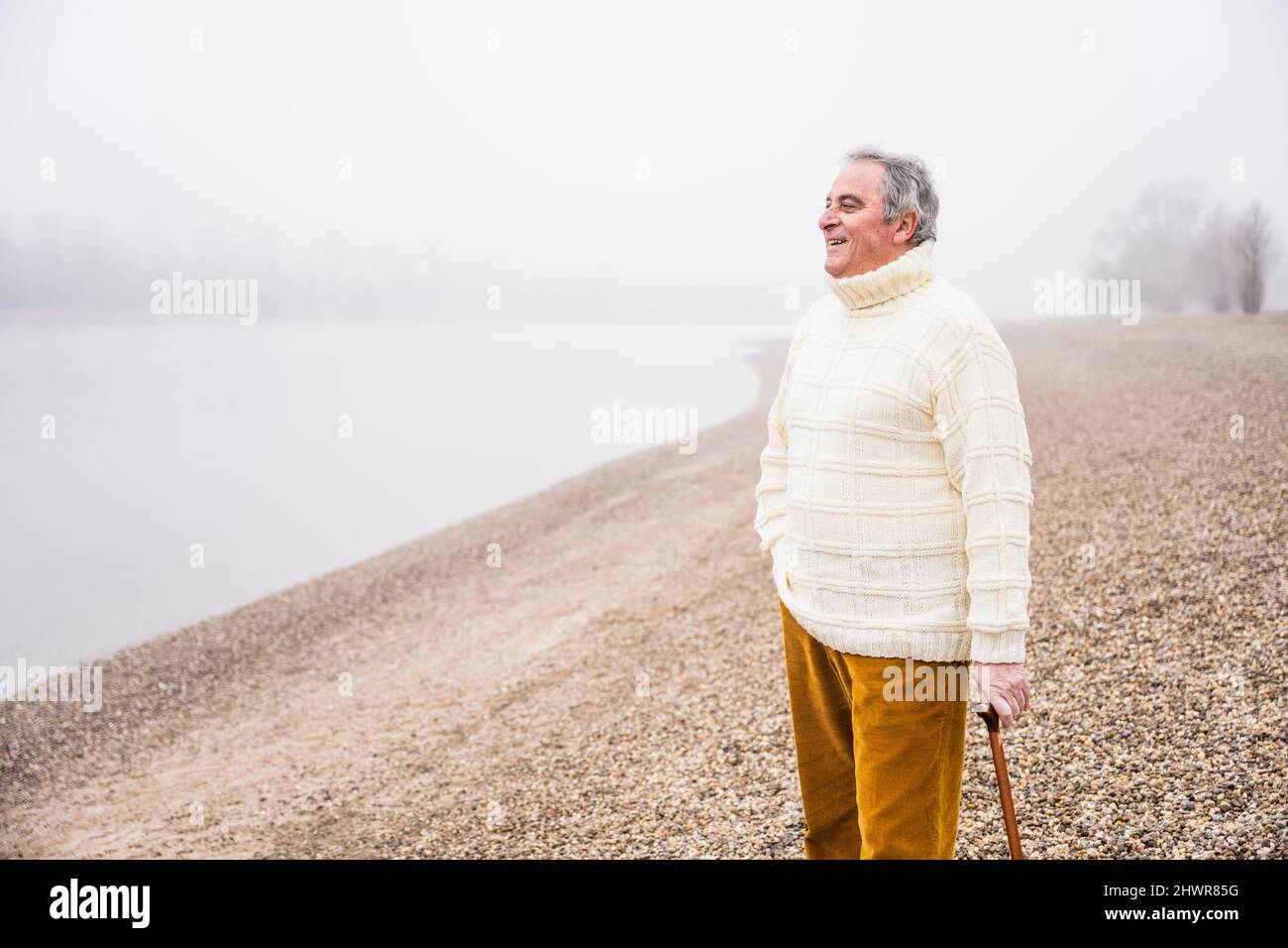 Smiling senior man with walking cane standing at beach Stock Photo Alamy