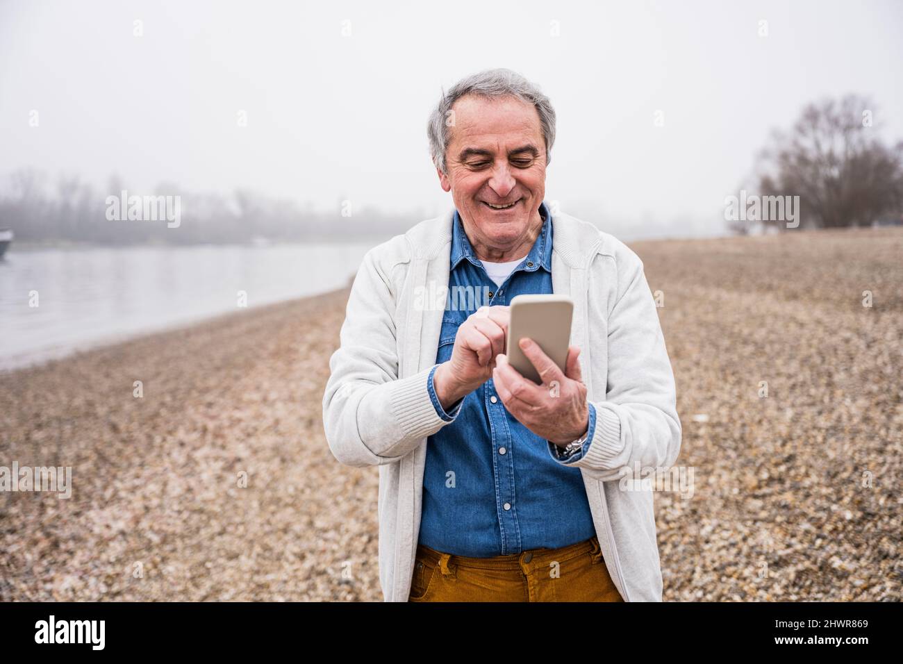 Happy senior man using mobile phone at beach Stock Photo