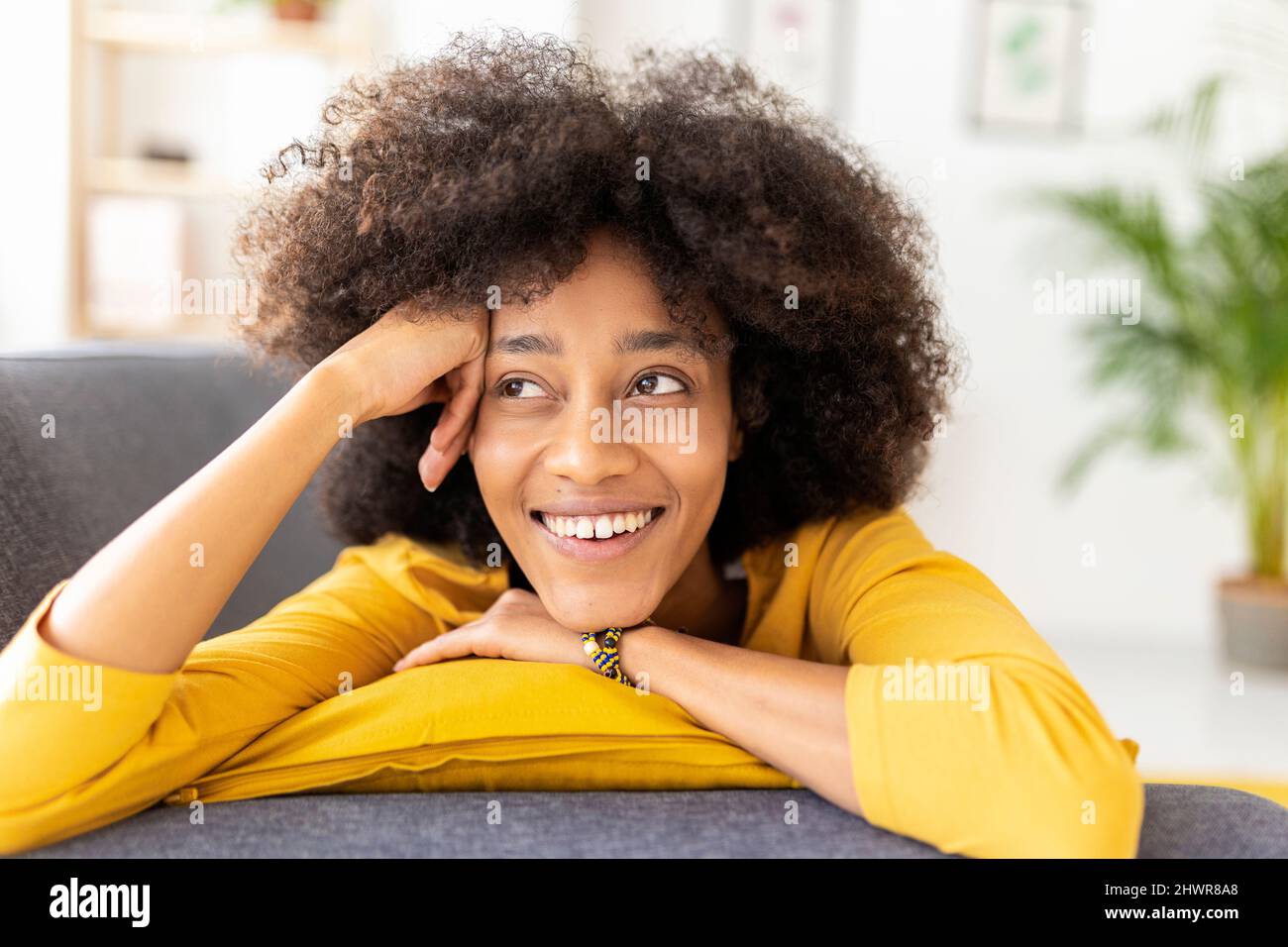 Happy woman lying on sofa at home Stock Photo - Alamy