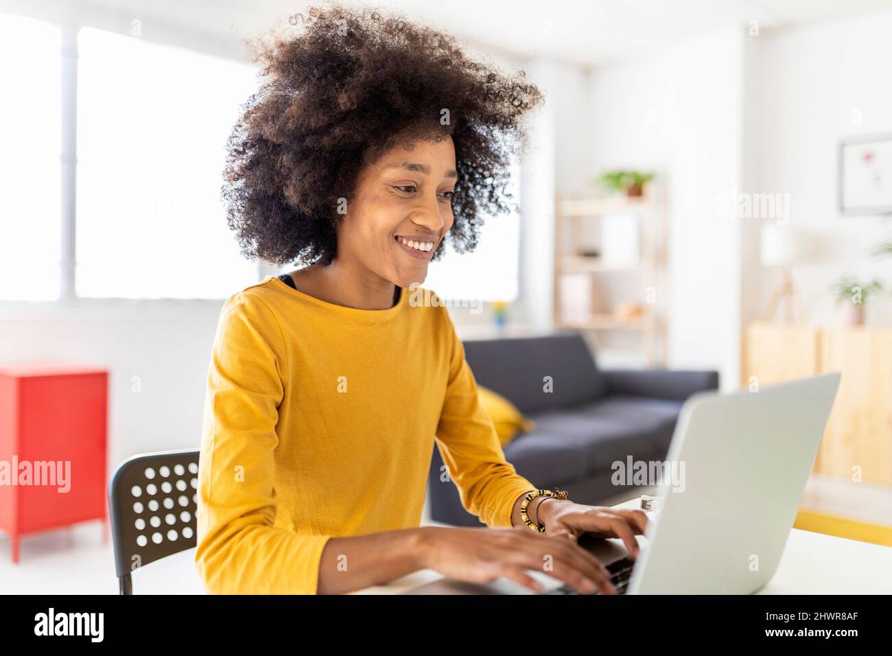 Happy young woman using laptop at home Stock Photo