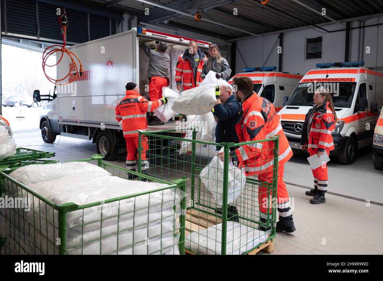 07 March 2022, Saxony, Dresden: Employees of Johanniter-Unfall-Hilfe in the  Dresden regional association load a truck with parts of a mobile refugee  shelter. The emergency shelter, consisting of 200 cots, is transported