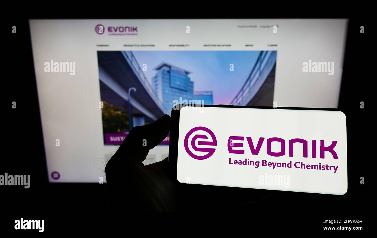 Person holding smartphone with logo of German chemicals company Evonik