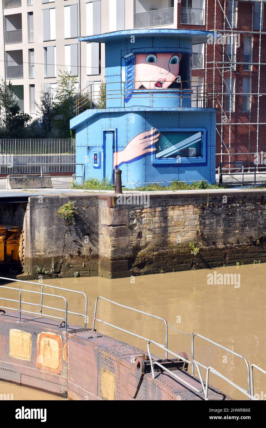 The control tower, of riveted steel, at the entrance to the Bordeaux floating harbour, now redundant & painted with a cartoon of a face trapped inside Stock Photo