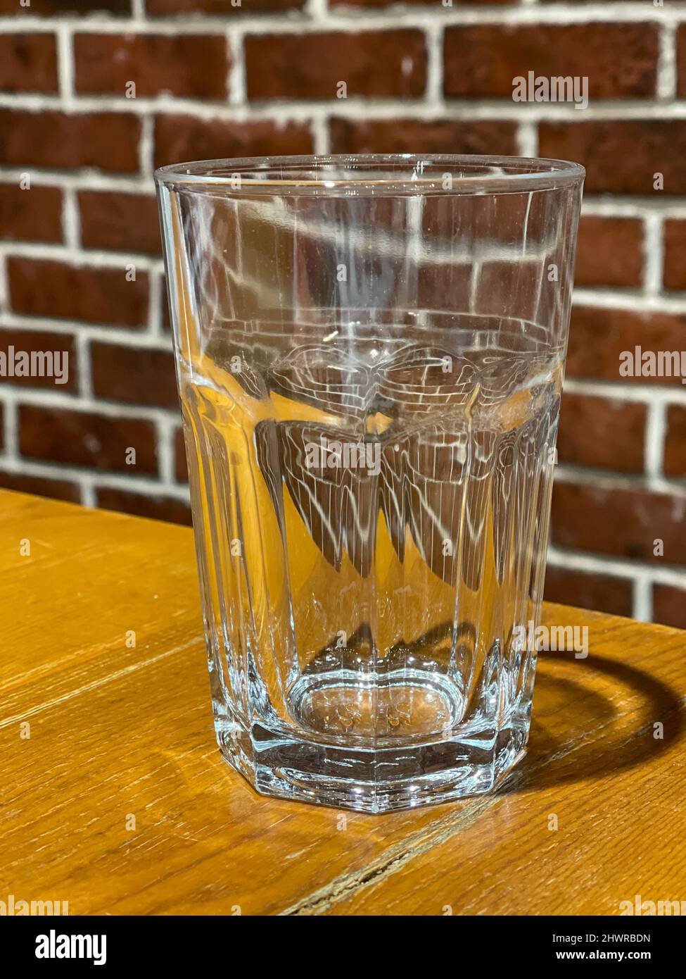 Close-up of an empty tall transparent glass on a wooden table. Stock Photo