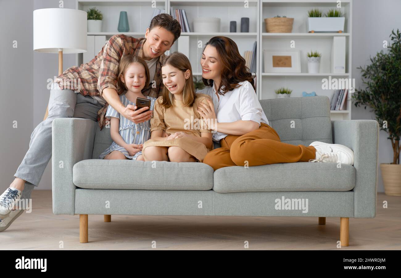 Happy loving family. Young mother, father and daughters using phone ...