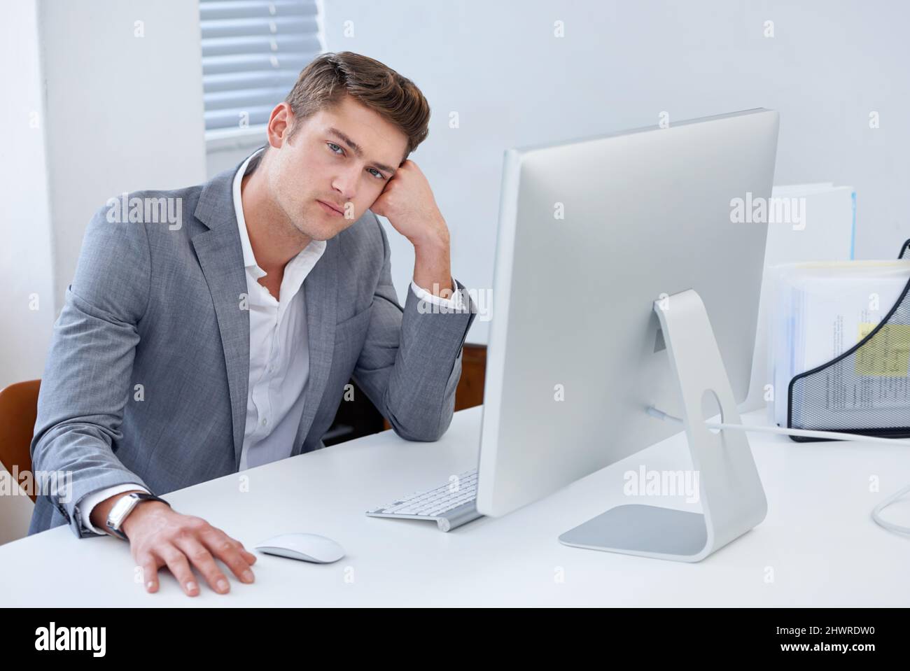 So unfulfilled at work. A bored young businessman seated at his desk. Stock Photo