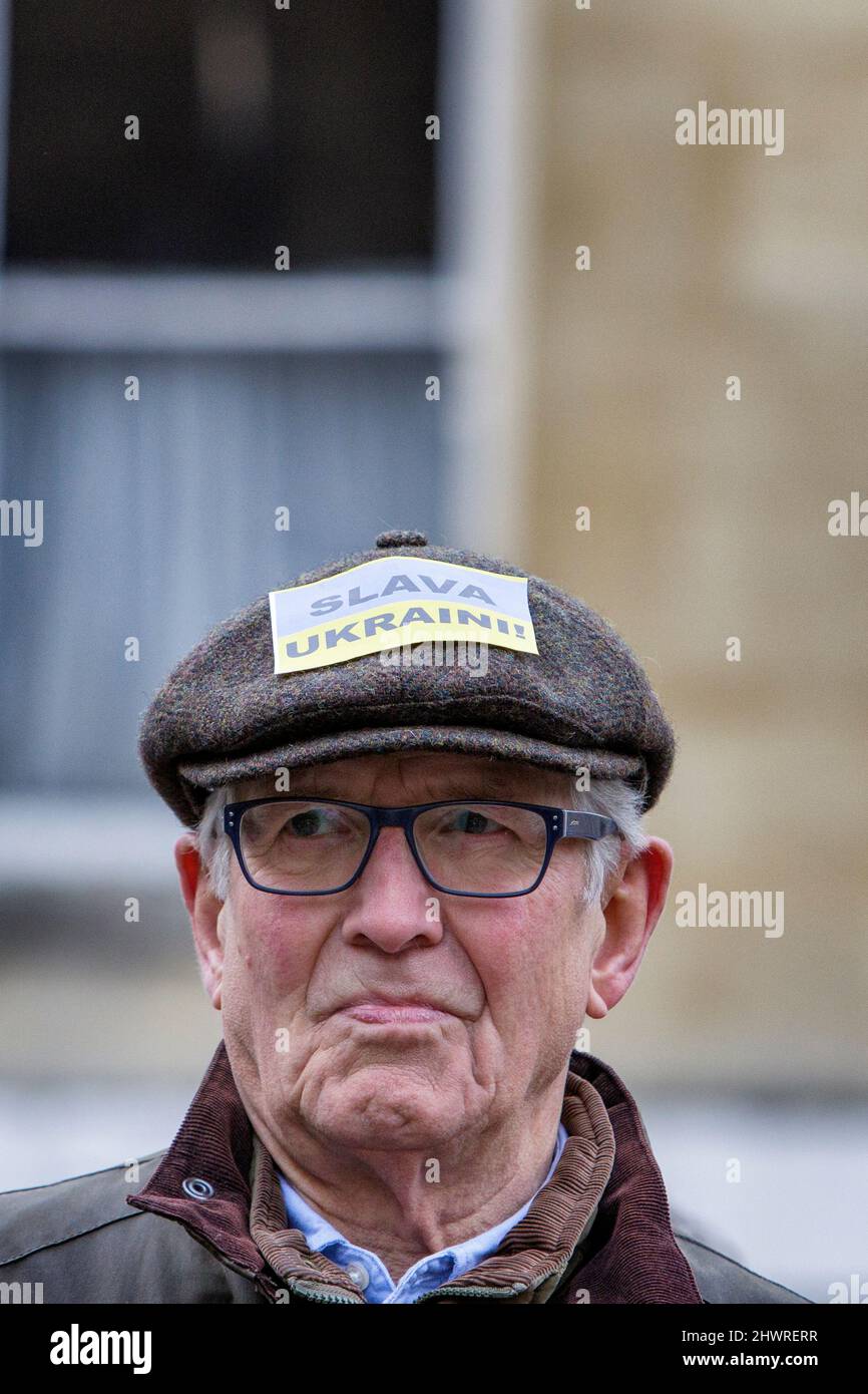 A man with a Slavia Ukraini! (Glory to Ukraine) sticker on his hat is pictured in front of Bath Abbey during a demonstration against Russia's invasion Stock Photo