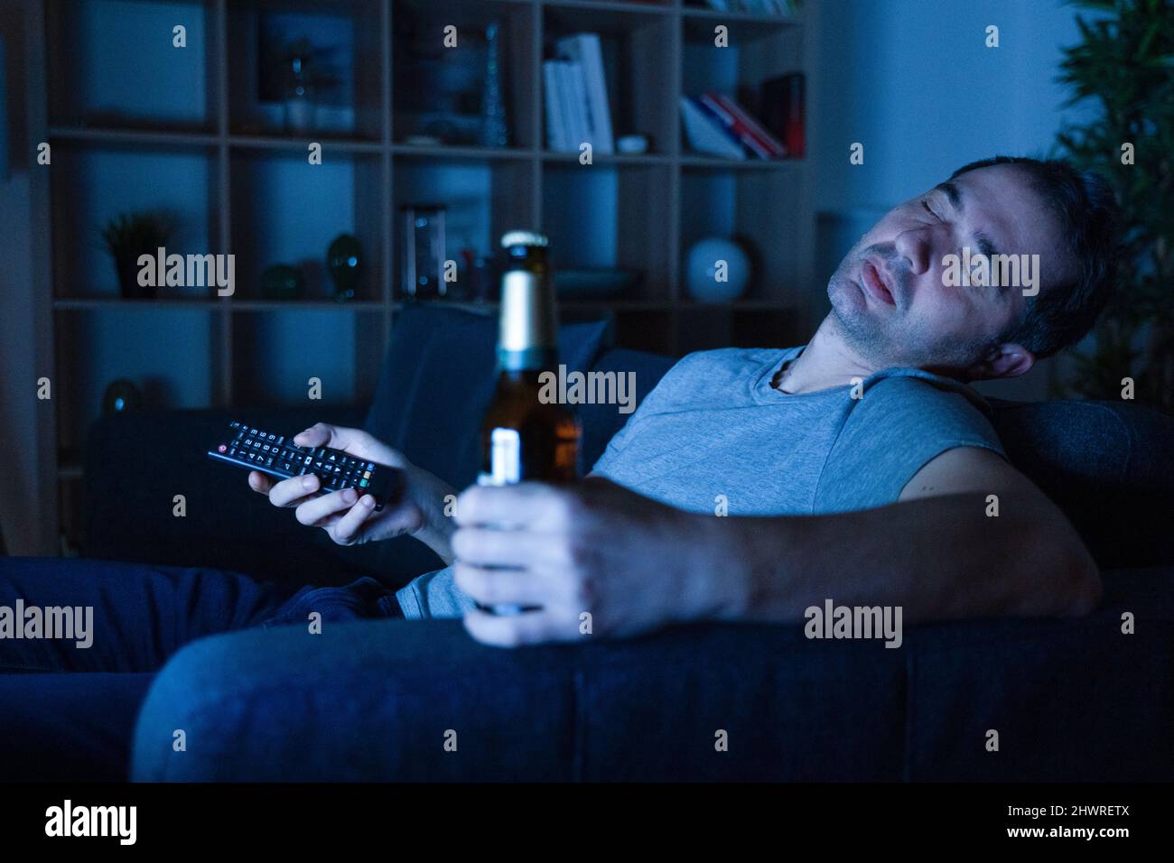 Man drinking alcohol at night on the sofa watching tv at home Stock Photo Alamy
