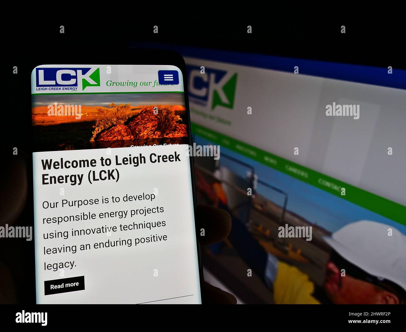 Person holding cellphone with web page and logo of company Leigh Creek