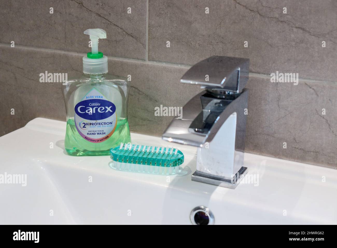 Chrome tap with Carex hand soap and nail brush Stock Photo