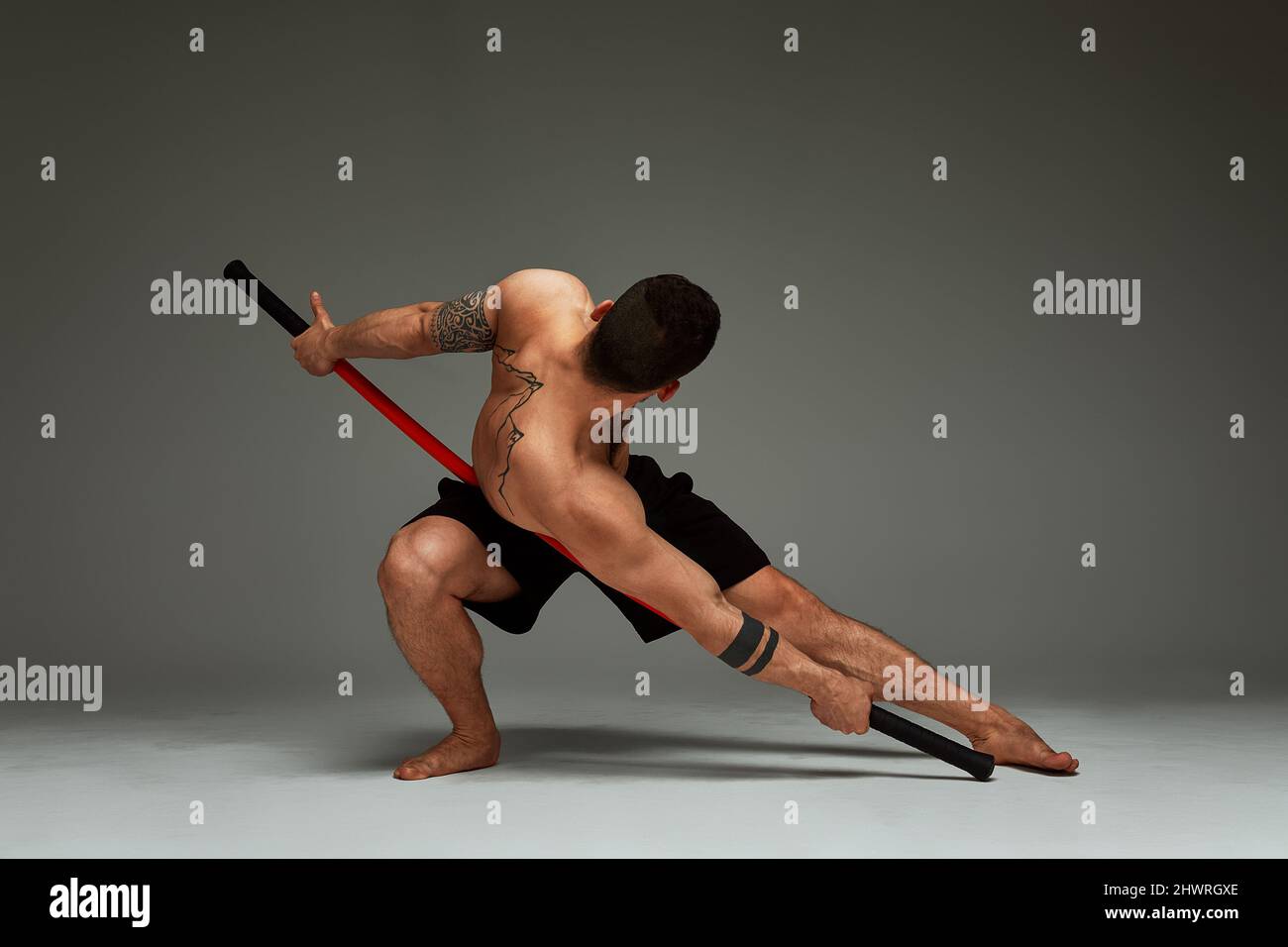 athlete men with stick training karate using sports tool in studio on