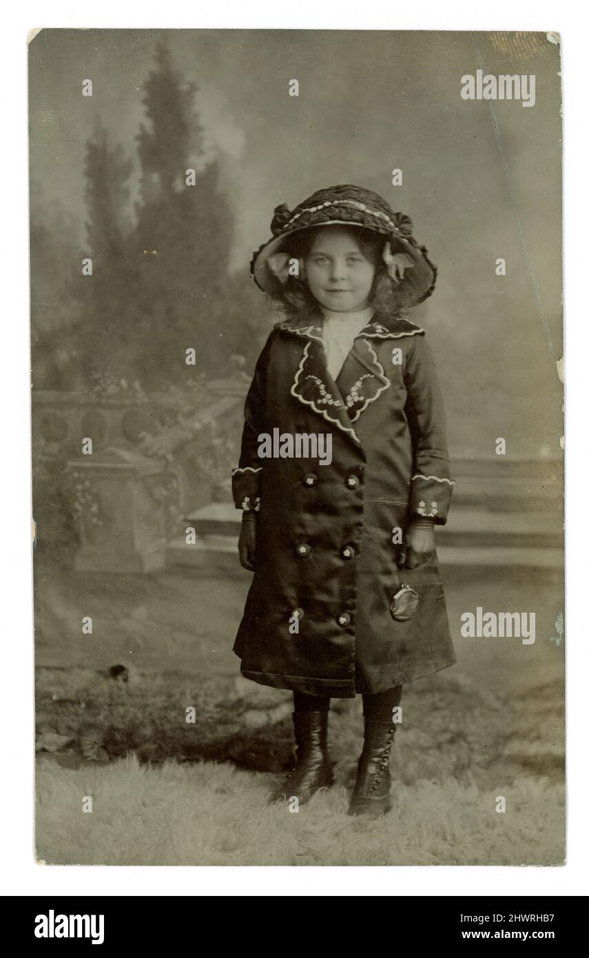 Original WW1 era postcard of a smartly dressed pretty young girl in a large hat and wearing a matching coat, wearing gloves and holding a purse. Photographed by Elizabeth Maria ‘Lizzie’ East, Park Lane Studio,  Caemawr Road, Morriston, Swansea, Wales, dated May 14 1914 Stock Photo