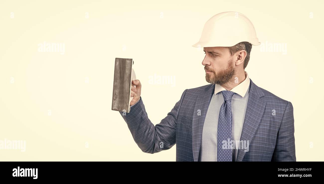 man in suit and safety helmet hold plaster trowel isolated on white copy space, plasterer. Stock Photo