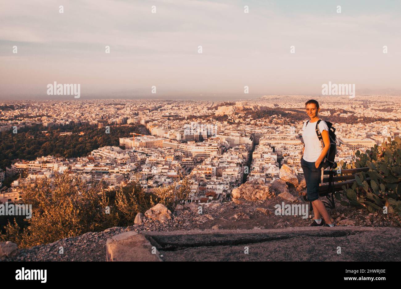 woman sitting on Lycabettus Hill, the highest point in the city overlooking Athens with the Acropolis - world traveller Stock Photo