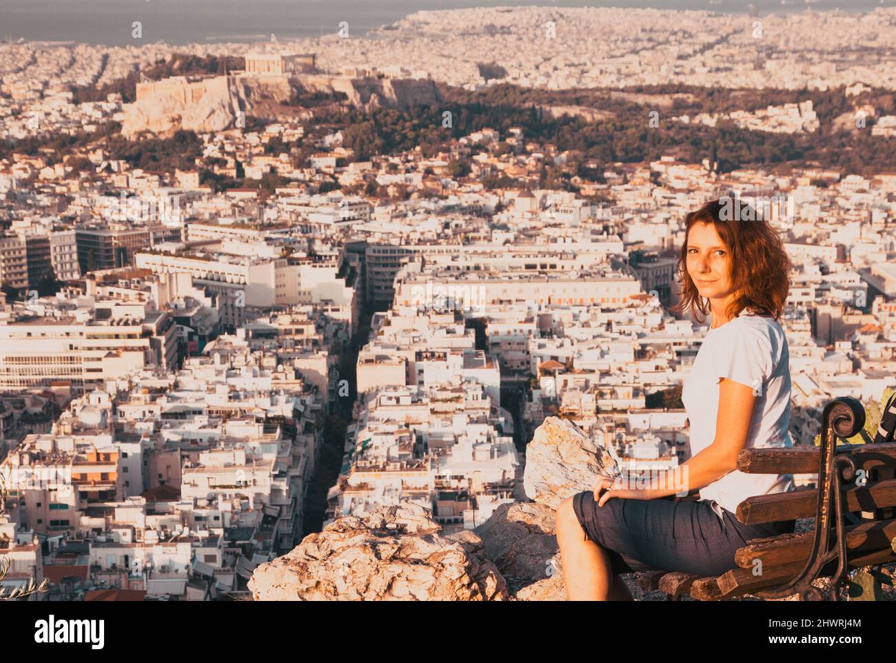woman sitting on Lycabettus Hill, the highest point in the city overlooking Athens with the Acropolis - world traveller Stock Photo