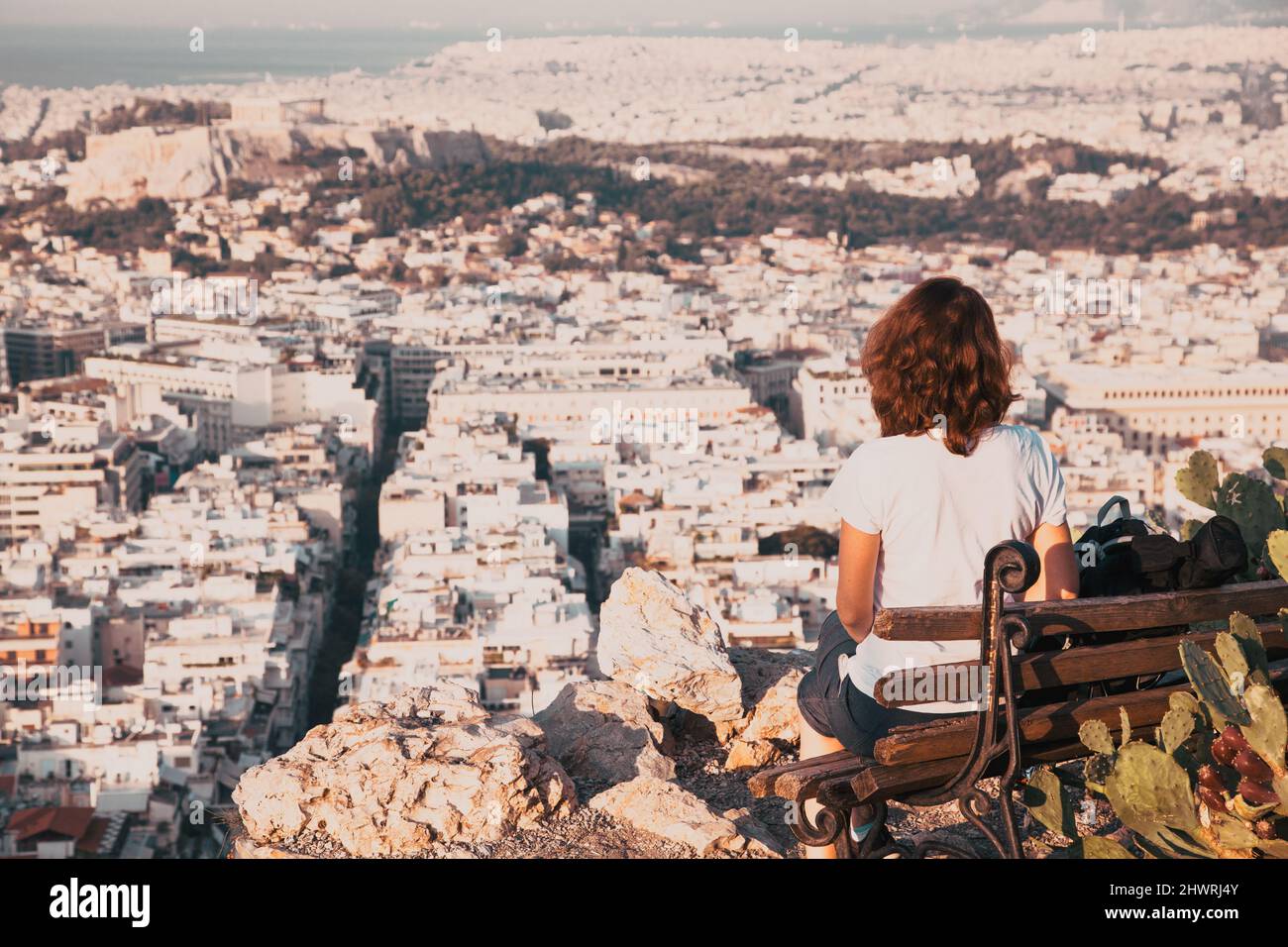 woman with a map sitting on Lycabettus Hill, the highest point in the city overlooking Athens with the Acropolis - world traveller Stock Photo