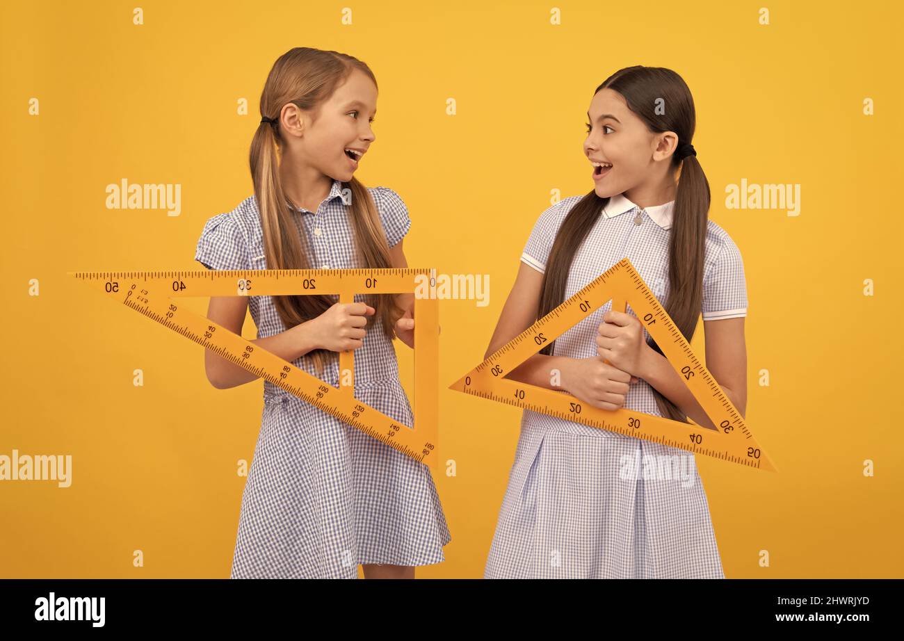 Happy school age children hold triangular rulers for geometry lesson, back to school Stock Photo