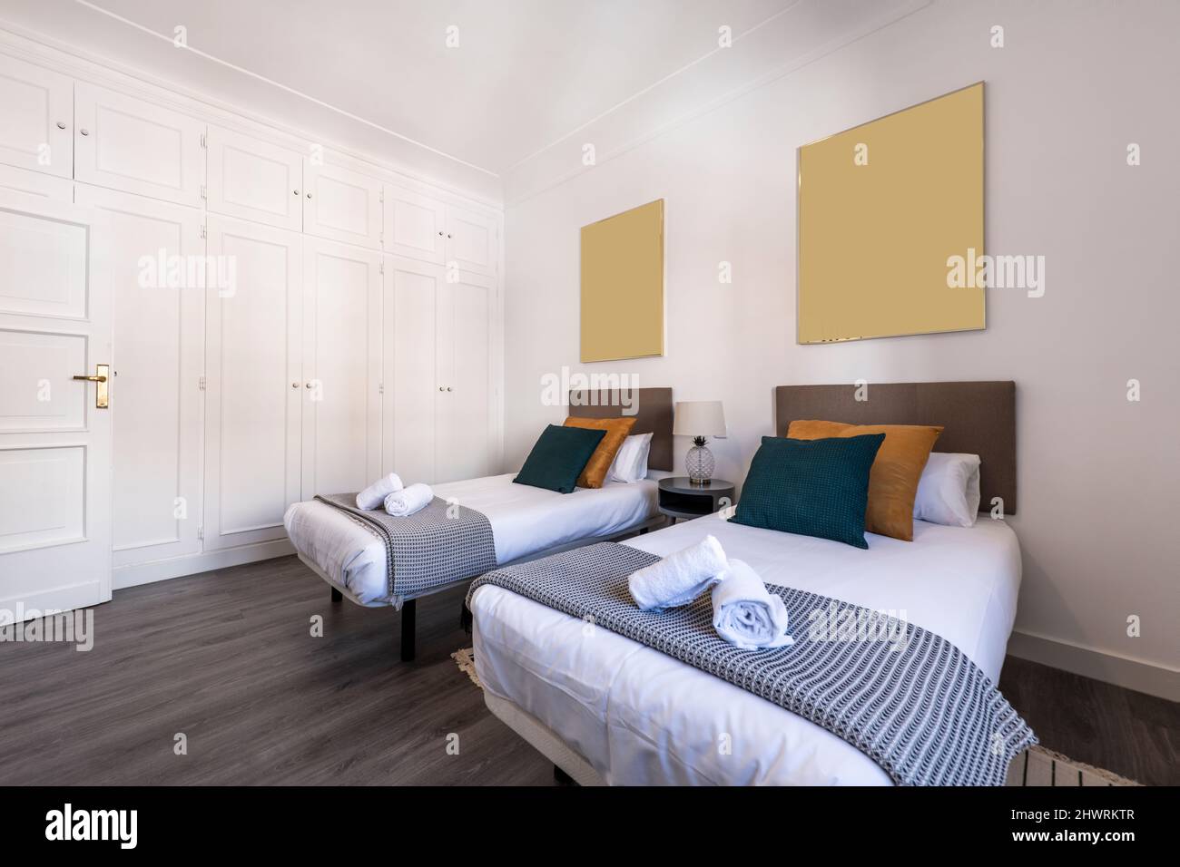 Bedroom with single beds, dark wooden floor, cushions, upholstered