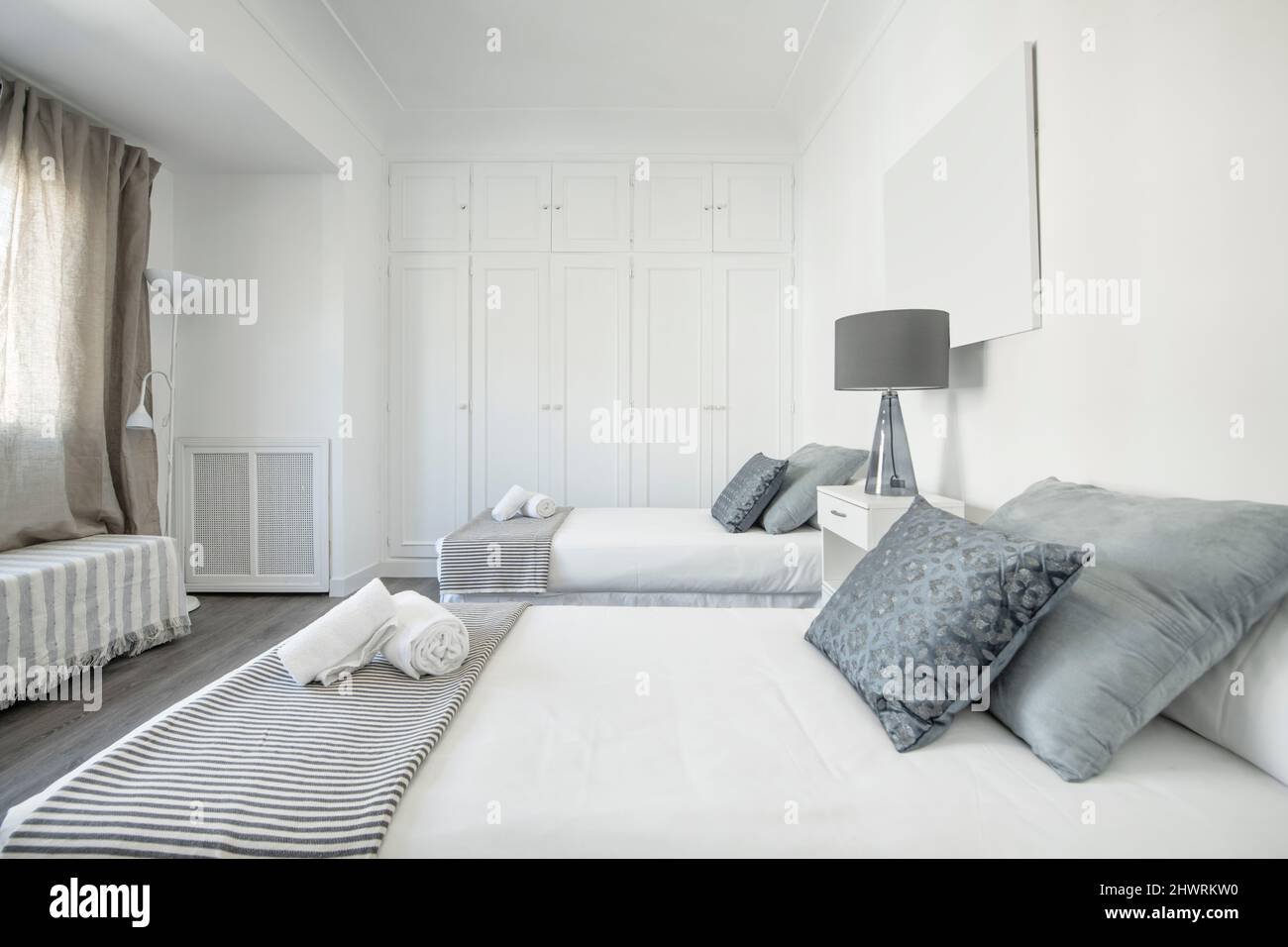 Bedroom with single beds, dark wooden floor, blue and gray cushions