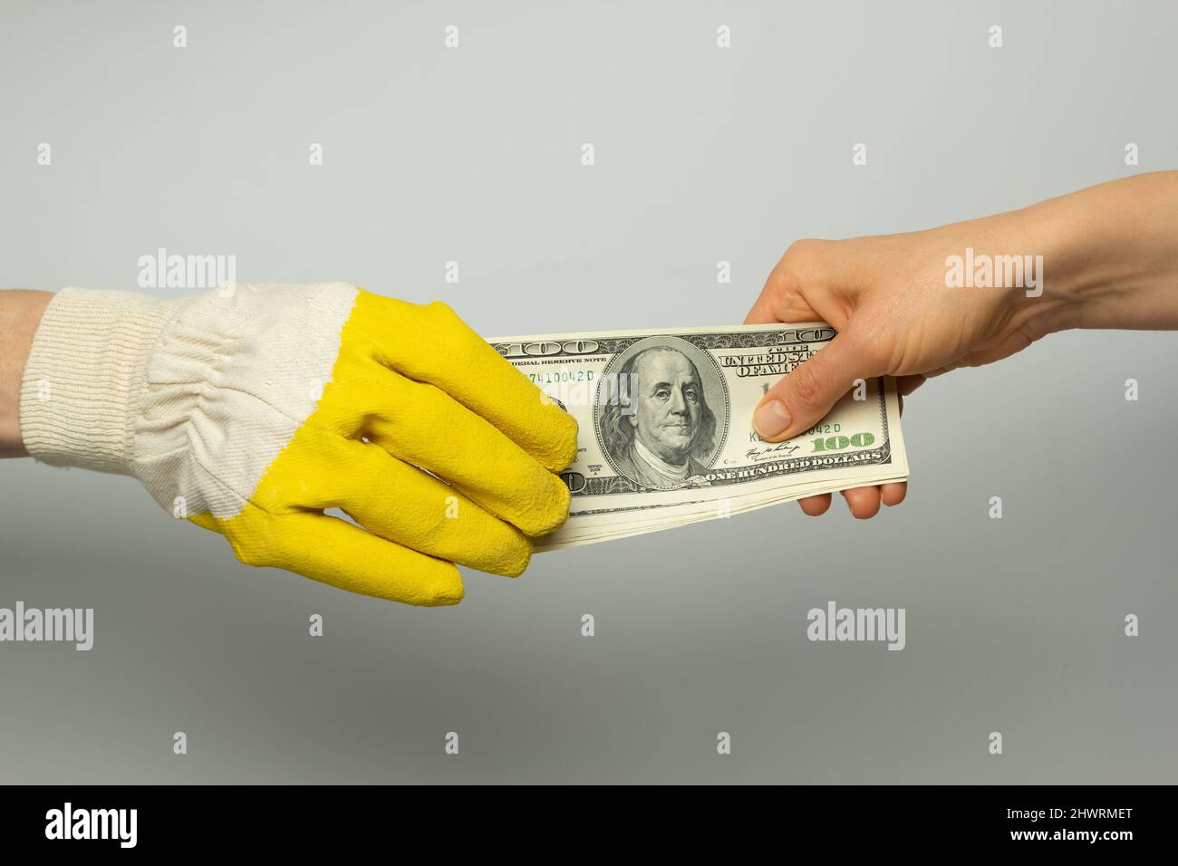The builder's hand in a protective glove takes money from the customer. Stock Photo