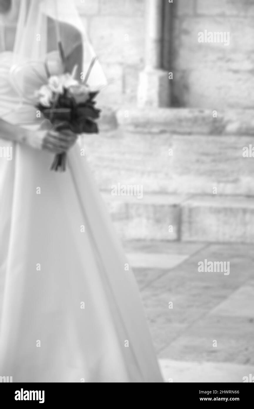 Blurred photo of bride entering to the Gothic church in her wedding day. Black and white. Stock Photo