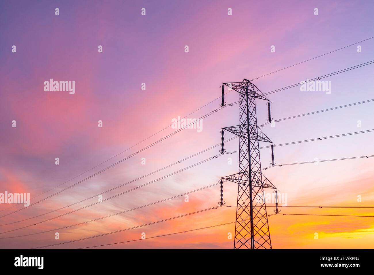 A low angle view of a metal electricity pylon carrying wires with large amounts of energy to supply business and homes with energy and copy space Stock Photo