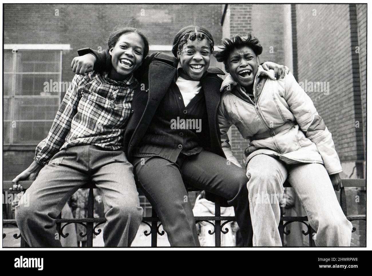 Three very happy teenagers pose for a photo on a schoolyard fence in Brooklyn, New York in 1981. Stock Photo