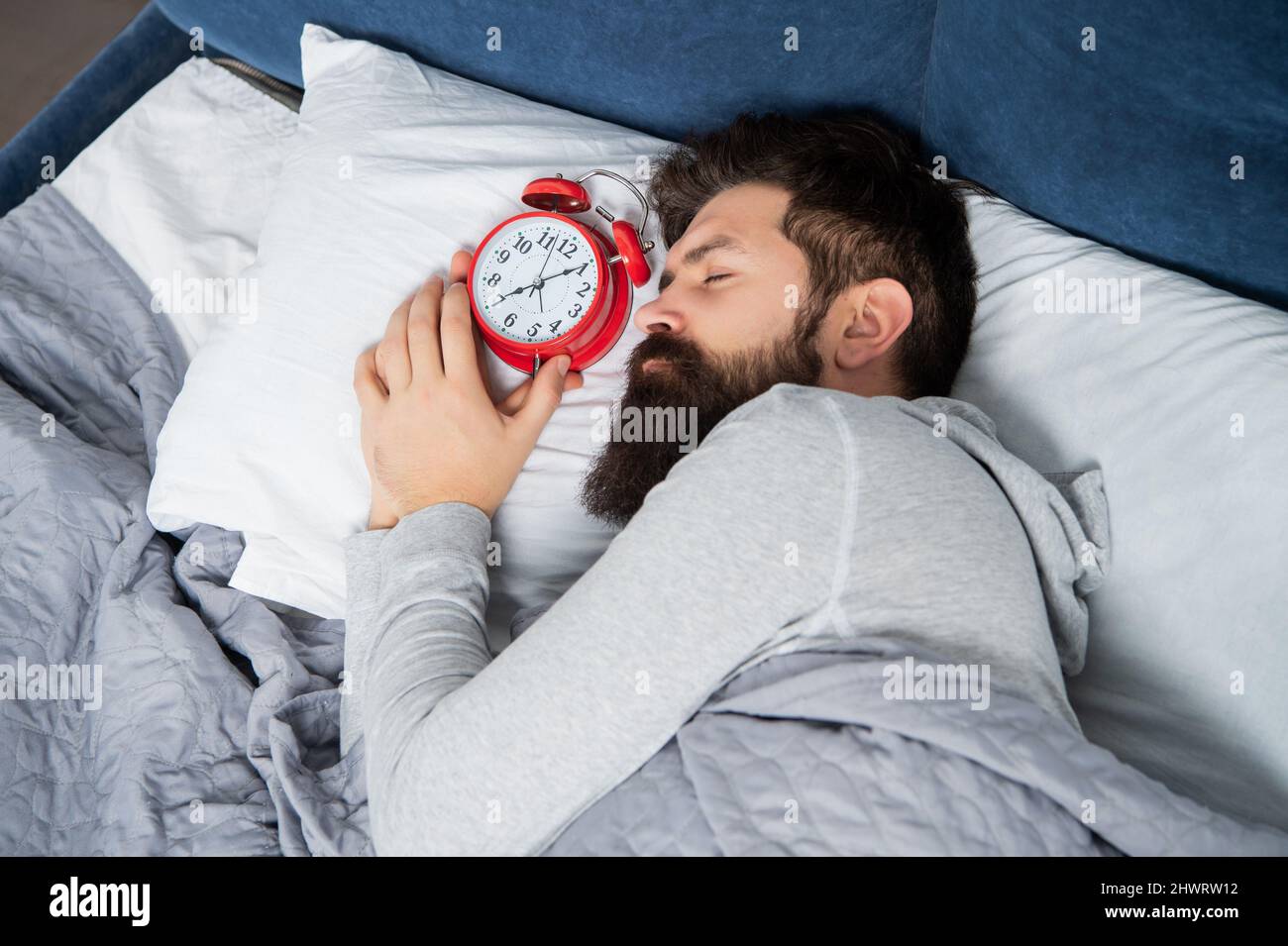 Man sleeping with alarm clock in bed, sleep time Stock Photo Alamy
