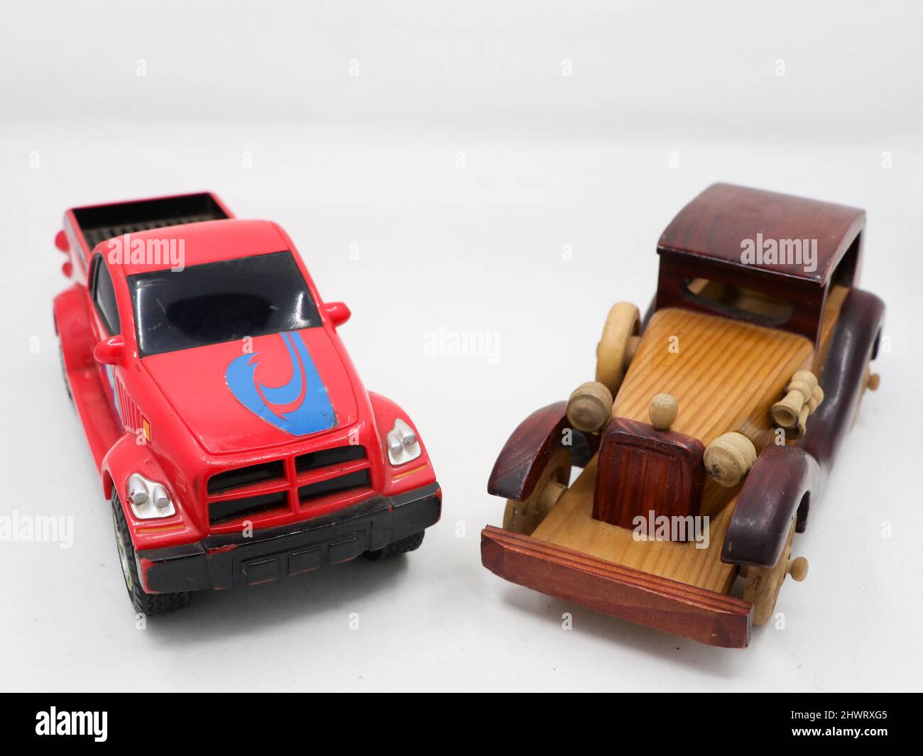 miniature toy models of a red tow truck and a brown wooden vintage car isolated in a white background Stock Photo