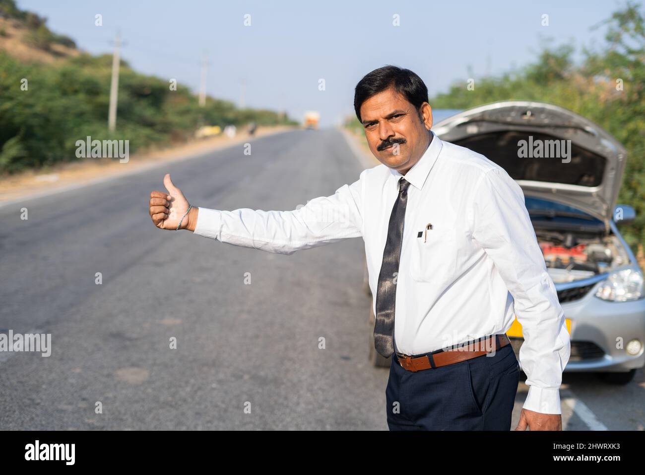 Businessman asking for lift or hitch hiking on road due to car
