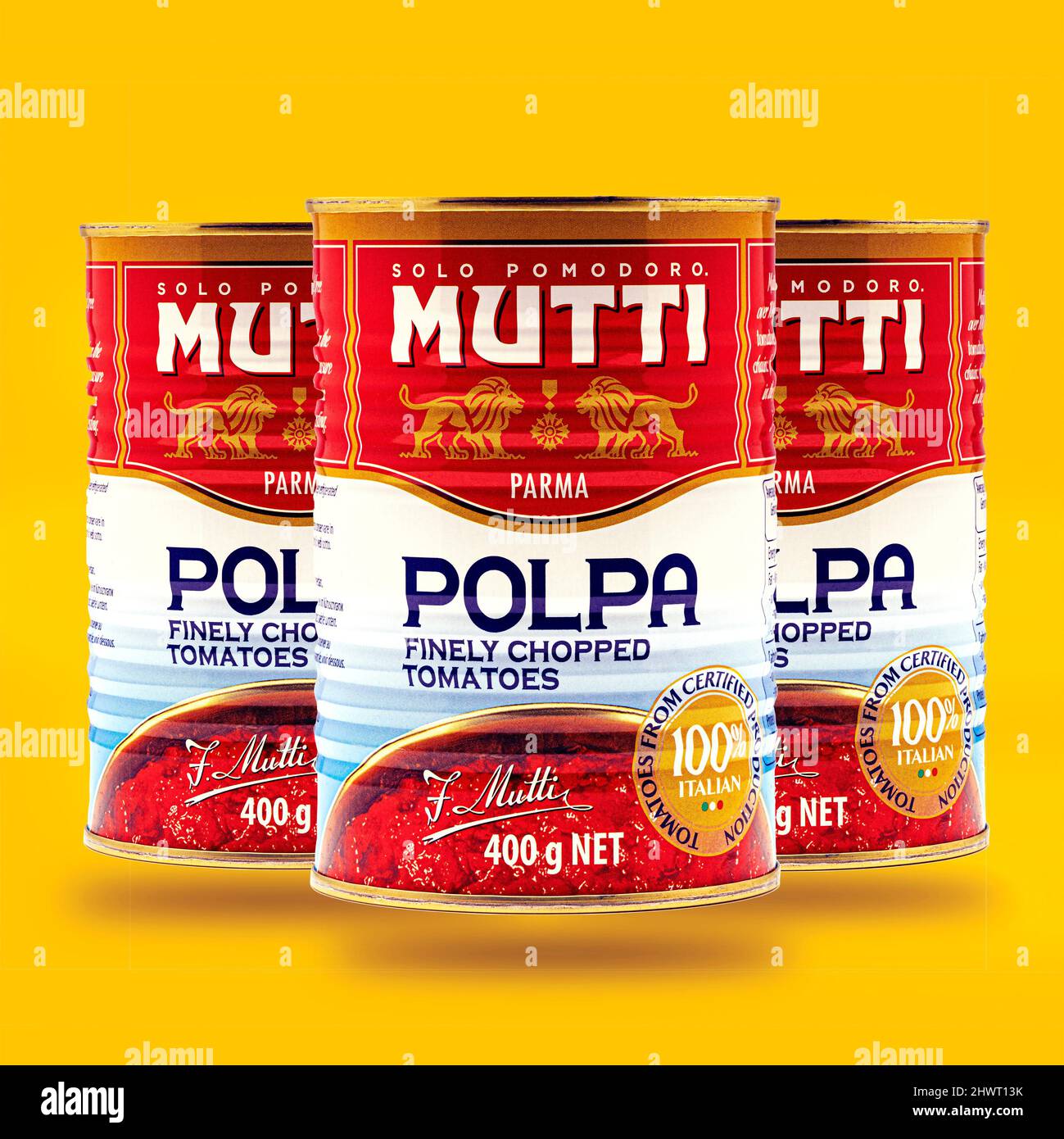 SWINDON, UK - MARCH 7, 2022: 3 Cans of Mutti Finely Chopped Tomatoes on a yellow background Stock Photo
