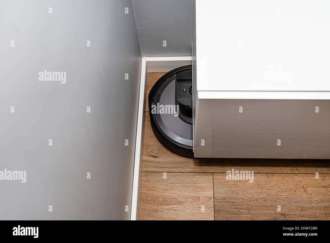 A modern robotic vacuum cleaner cleans vinyl panels under bedroom