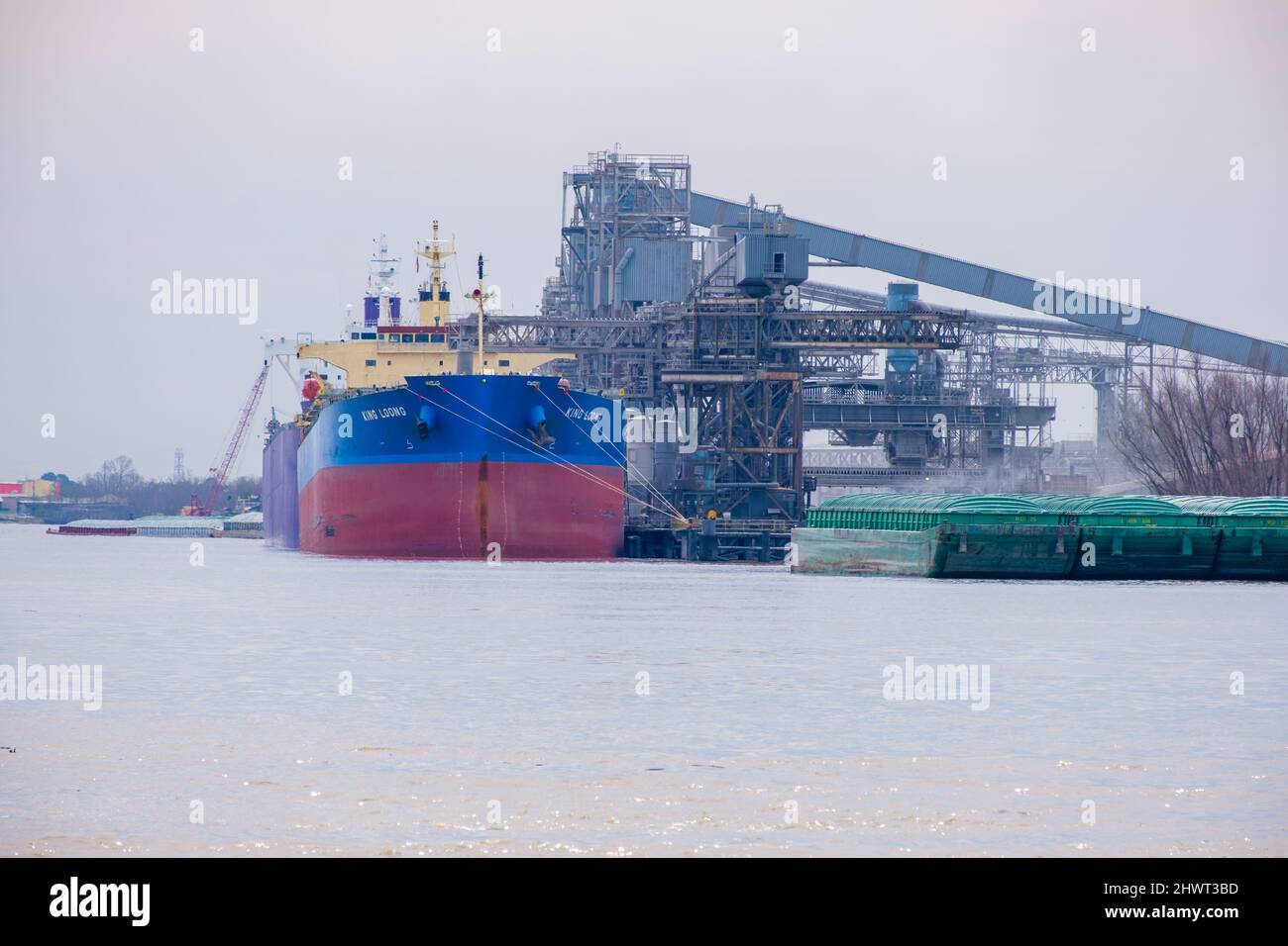 WESTWEGO, LA, USA - MARCH 3, 2022: Bulk Carriers and barges alongside grain elevator on the Mississippi River just outside of New Orleans Stock Photo