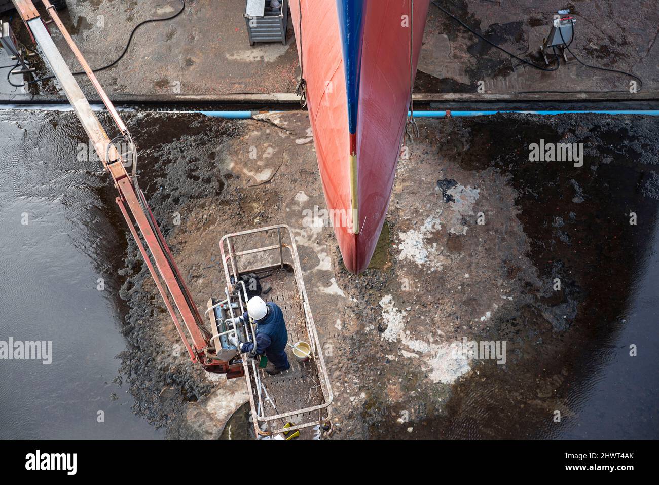 Closeup of a man renovating a ship in a dry dock in the port of Saint