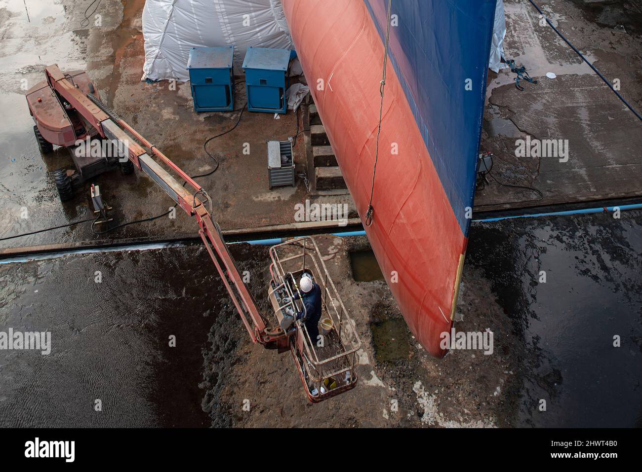 Closeup of a man renovating a ship in a dry dock in the port of Saint