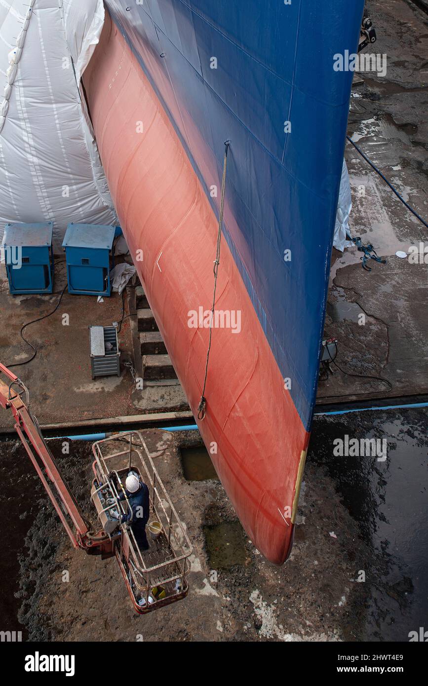 Closeup of a man renovating a ship in a dry dock in the port of Saint