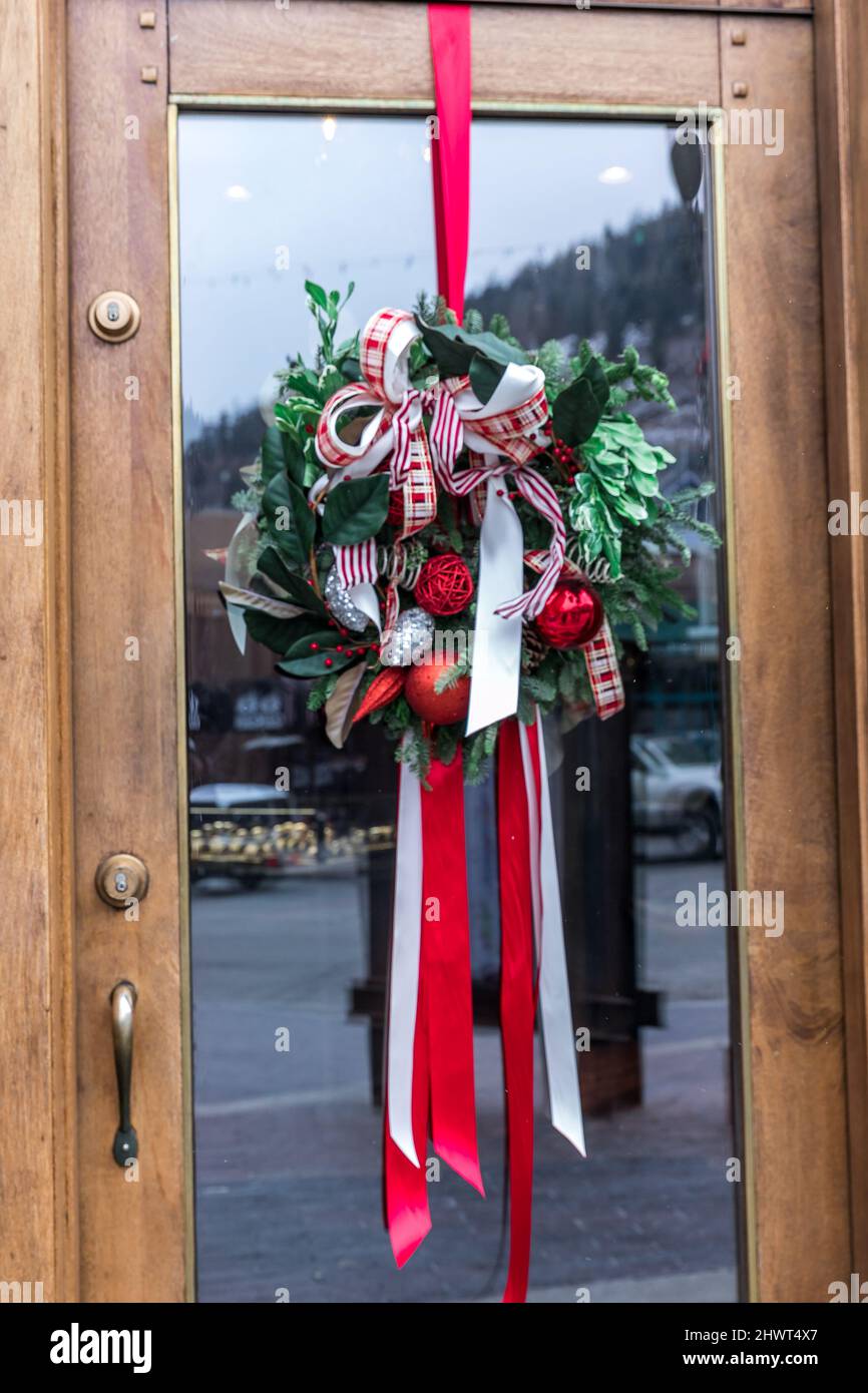 A Christmas wreath with ribbon hanging from a glass entrance door as winter December outdoor decor Stock Photo