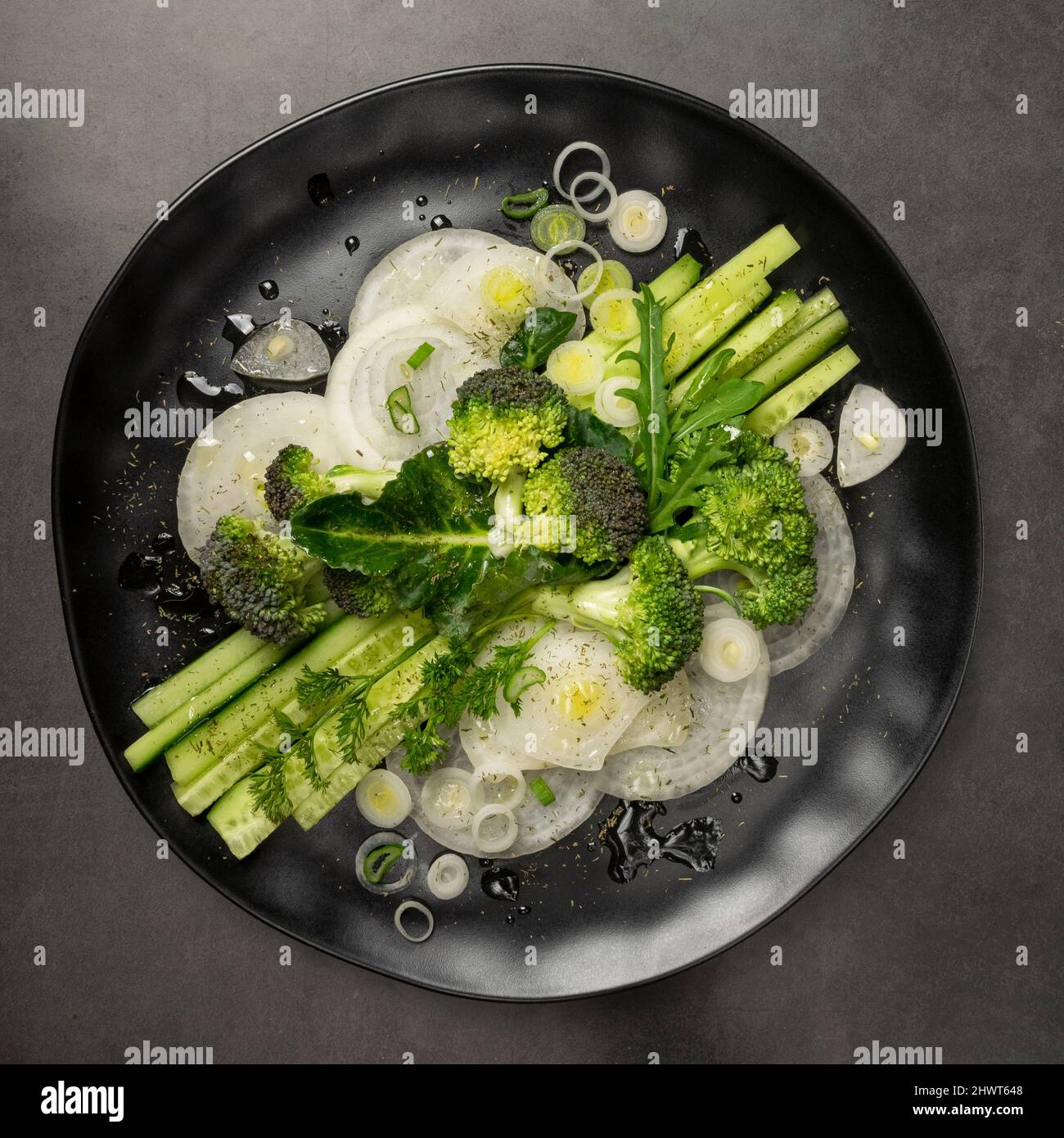 Geometric fresh salad with greenery. Black plate on black background, healthy eating concept Stock Photo
